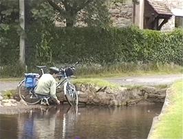 James cleans his bike in the duck pond at East Quantoxhead